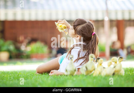 ute girl lying down on grass and holding spring duckling Stock Photo