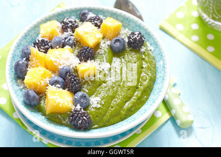 Breakfast green smoothie bowl topped with mango, bluebery and blackberry Stock Photo
