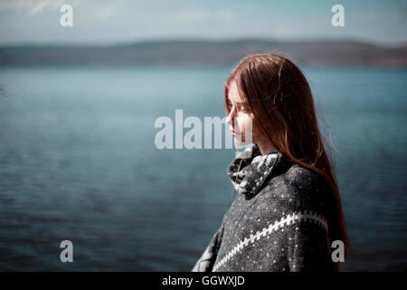 Pensive Caucasian girl at lake Stock Photo