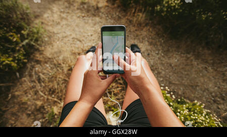 Close up shot of woman runner using a fitness app on her smartphone. Female checking the summary of her run on mobile phone. POV Stock Photo