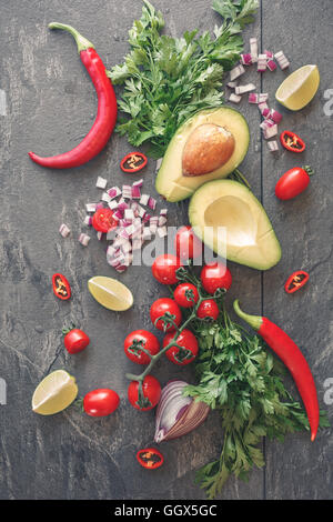 Fresh ingredients for a delicious guacamole over grey background. Top view, vintage toned image, blank space Stock Photo