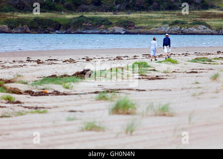 A couple enjoying a walk along the shoreline of Newborough Beach, Anglesey, Wales, UK Stock Photo