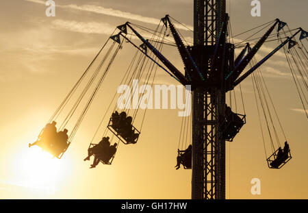 People enjoying swing ride at sunset Stock Photo