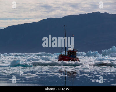 Small tourist boat sailing through icebergs of Qooroq Ice Fjord Tunulliarfik Fjord Southern Greenland fed by Greenland ice sheet glacier awesome view Stock Photo