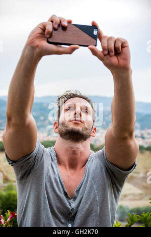 Waist Up of Young Attractive Smiling Man Taking Selfie Self Portrait with Cell Phone in Outdoors Stock Photo