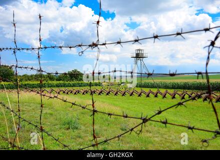 View through the barbed wire fence on watchtower and line of defense and military territory near state border. Memorial military Stock Photo