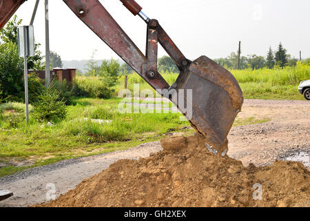 Excavator bucket digging a trench in the dirt ground. Stock Photo