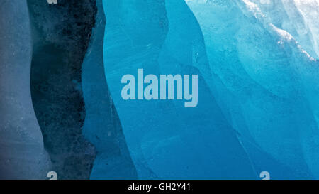 Dirt and gravel turn a seam of glacier ice black unlike the ice which glows in various shades of blue. Stock Photo