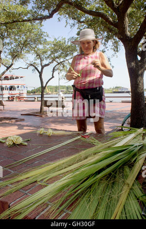 Savannah native crafting palm frond roses on the historic riverfront. Stock Photo
