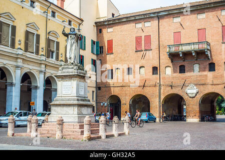 Cyclists crossing Piazza Savonarola square with Savonarola statue in Ferrara, Emilia-Romagna. Italy Stock Photo