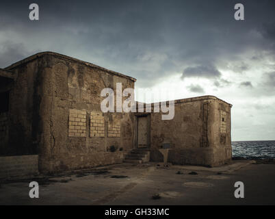 Old abandoned building with bricked up windows on the Mediterranean coast in Sicily Stock Photo