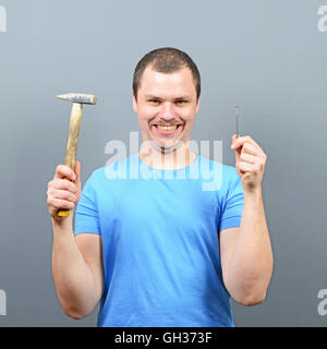Portrait of funny man holding hammer and nail Stock Photo