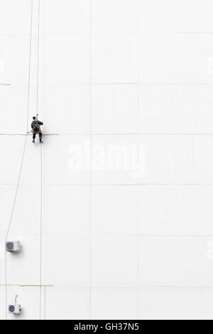 Maintenance worker climbing outside a wall Stock Photo