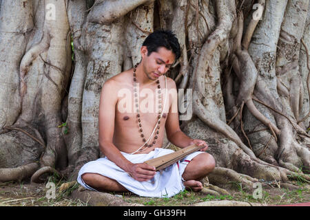 A young traditional ayurvedic doctor reading an ancient palm-leaf scroll on natural medicine. Stock Photo