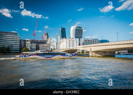 Pleasure boats passing under London Bridge on a sunny day with the Walkie Talkie, Cheesgrater and Tower 42 skyscrapers in the background, England, U.K. Stock Photo