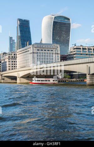 Pleasure boats passing under London Bridge on a sunny day with the Walkie Talkie, Cheesgrater and Tower 42 in the background. Stock Photo