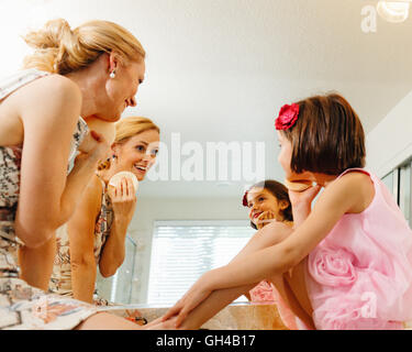 Low Angle View of a Mother and Daughter in the Bathroom Practicing Applying Make Up Stock Photo
