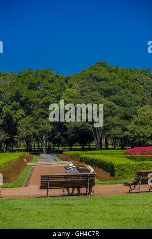 CURITIBA ,BRAZIL - MAY 12, 2016: people resting on a bench at the geometrical gardens of the botanical park of the city Stock Photo