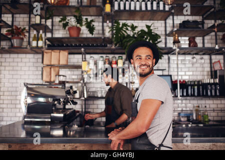 Coffee shop owner standing with barista working behind the counter making drinks. Stock Photo