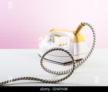 Yellow steam smoothing iron on pink background. Single object with clipping path Stock Photo