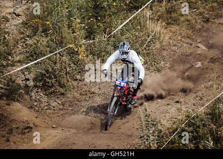 young rider athlete on bicycle rides along a dusty trail during National championship downhill Stock Photo