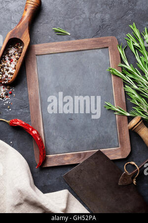Herbs and spices cooking on stone table. Rosemary, pepper and salt. Top view with blackboard for your text Stock Photo
