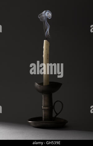 Blown Out Smoking Candle on Iron Candlestick Stock Photo
