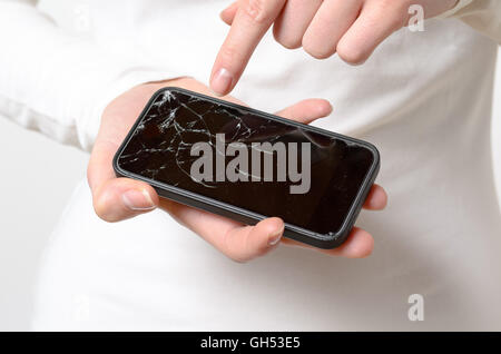 Close up of one woman in white blouse holding broken mobile phone in her hands Stock Photo