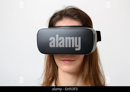 Close up of calm woman in brown hair wearing virtual 3d device on face over gray background Stock Photo