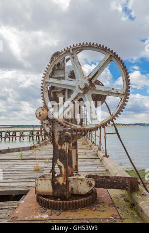 The slowly decaying piers at Shotley Gate in Suffolk old crane on harbour Stock Photo