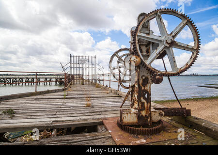 The slowly decaying piers at Shotley Gate in Suffolk old crane on harbour Stock Photo