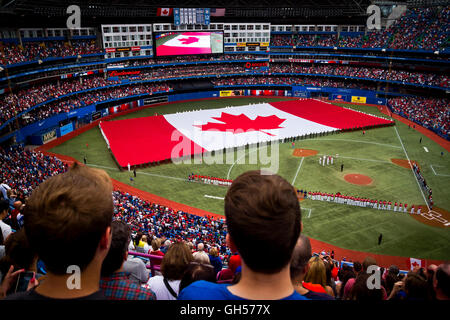The crowd watches a Canadian flag being rolled out while the national anthems are sung on Canada Day at the Rogers Centre in Toronto, Canada. Stock Photo