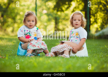 The two little baby girls sitting on pots Stock Photo