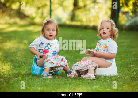 The two little baby girls sitting on pots Stock Photo