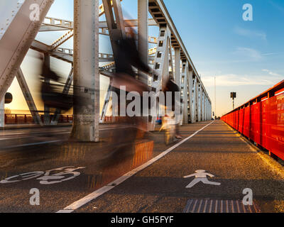 Crossing the bridge by bike in the evening sun between Dordrecht and Zwijndrecht. Stock Photo