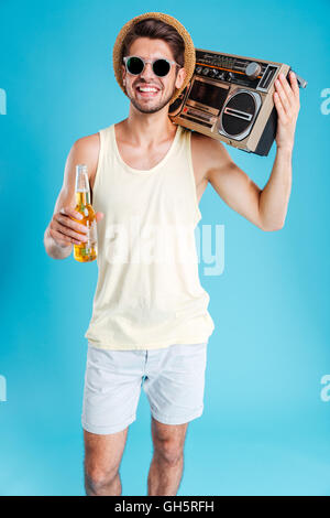 Smiling handsome young man in hat and sunglasses with boombox and bottle of beer Stock Photo