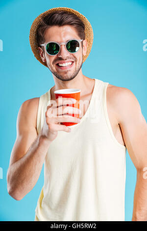 Portrait of smiling young man in hat and sunglasses drinking coffee Stock Photo