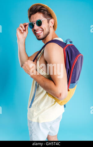 Portrait of smiling young man in hat and sunglasses with backpack Stock Photo