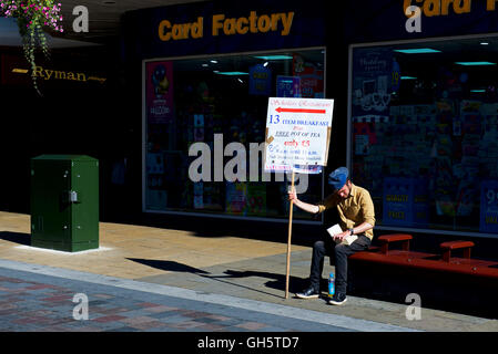 Young man holding up sign advertising breakfasts and a local café, Darlington, County Durham, England UK Stock Photo
