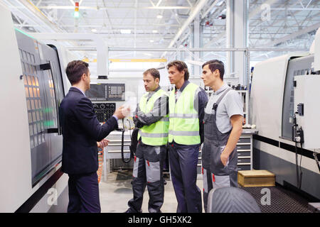 Manager and workers at plant near CNC machines Stock Photo
