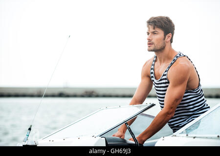 Young handsome bearded sailor man driving his motor boat Stock Photo