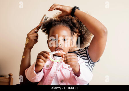 modern young happy african-american family: mother combing daughters hair at home, lifestyle people concept Stock Photo