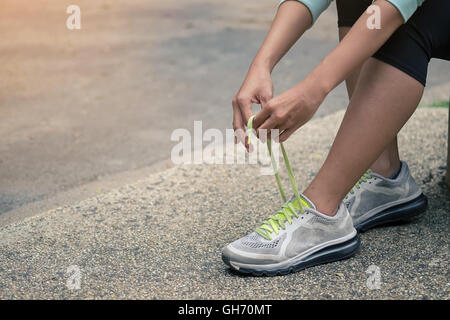 Running shoes - closeup of woman tying shoe laces. Female sport fitness runner getting ready for jogging outdoors on forest path Stock Photo