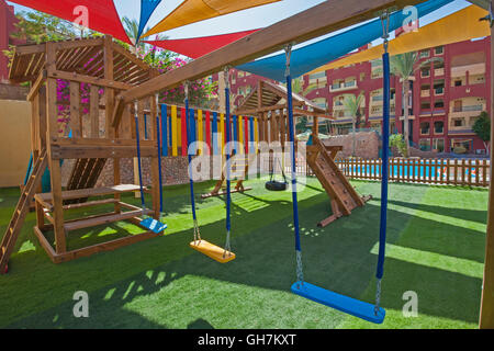 Childrens outdoor playground area at tropical hotel resort with climbing frame and swings Stock Photo