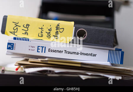 Hanover, Germany. 05th Aug, 2016. A binder written with 'asylum decisions' can be seen on a desk in an office from the Network for Traumatized Refugees in Lower Saxony behind the psychological questionnaire 'Essen Trauma Inventory' in Hanover, Germany, 05 August 2016. The Network for Traumatized Refugees in Lower Saxony sees to the urgent treatment and placement in psychological care for traumatized refugees. Photo: SEBASTIAN GOLLNOW/dpa/Alamy Live News Stock Photo
