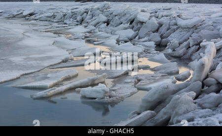 Tidal action has broken the ice up into sheets and pushed it up on to the shore Stock Photo