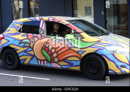 A couple driving in a colourful rental car Stock Photo