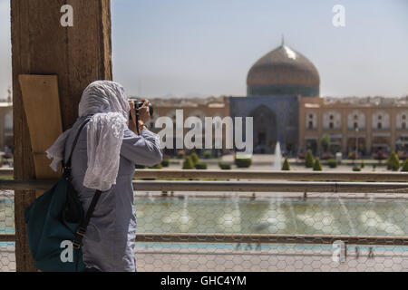 A Lady is taking pictures from Naqsh-e Jahan Square with a background Sheikh Lotfollah Mosque in Isfahan, Iran Stock Photo