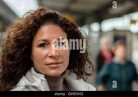 Attractive young woman travelling on a train looking at the camera with a quiet smile, close up head shot Stock Photo