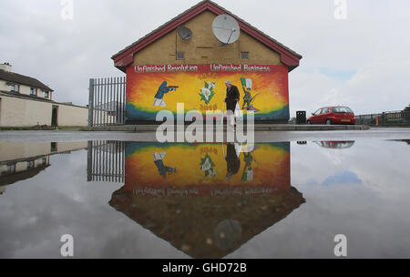A woman walks past a newly painted Republican mural commemorating the 1916 Easter Rising in the Creggan area of Londonderry. Stock Photo